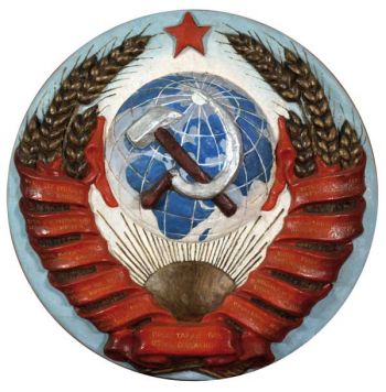 Герб СССР со звездой, эмблемой «серп и молот», лозунгом на ленте «Пролетарии всех стран, соединяйтесь!» и переводом лозунга на национальные языки республик.